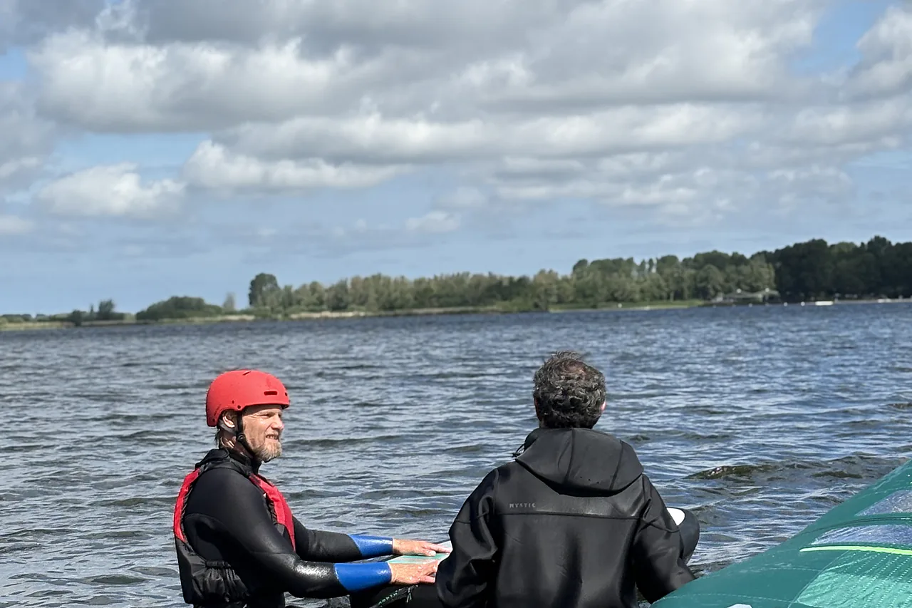 Instructor coaching a wingfoil student in the water